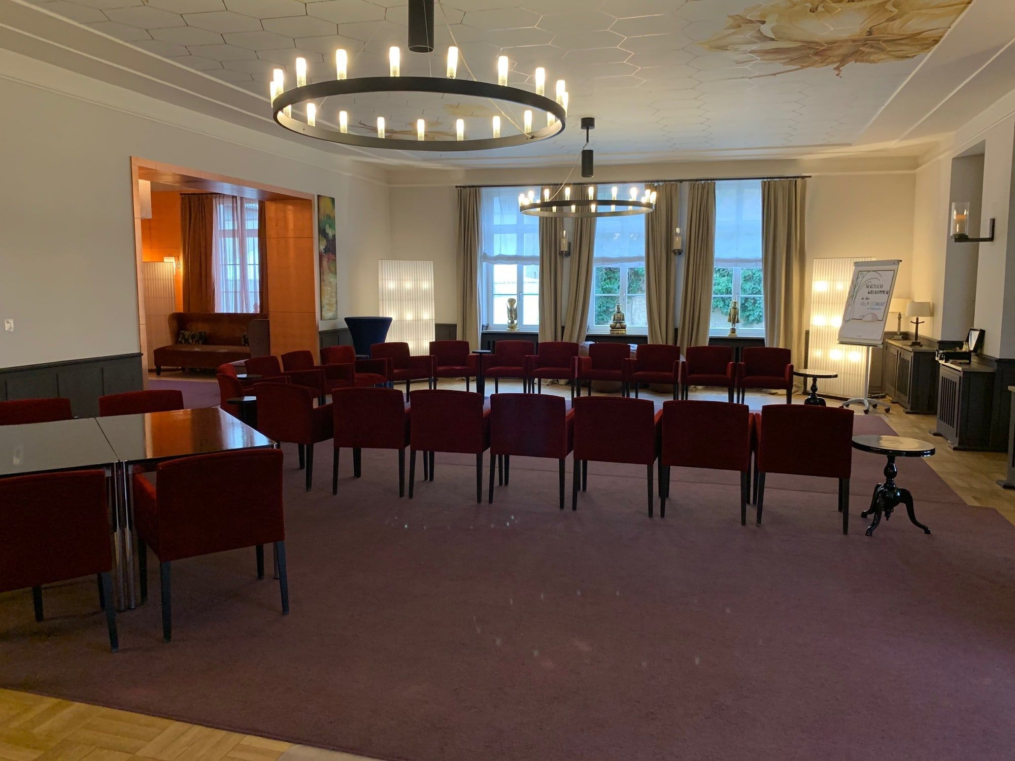 Der Große Saal der Villa Leonhart in Königswinter mit bemalter Decke, Kronleuchtern, Parkett und hohen Fenstern zum Park