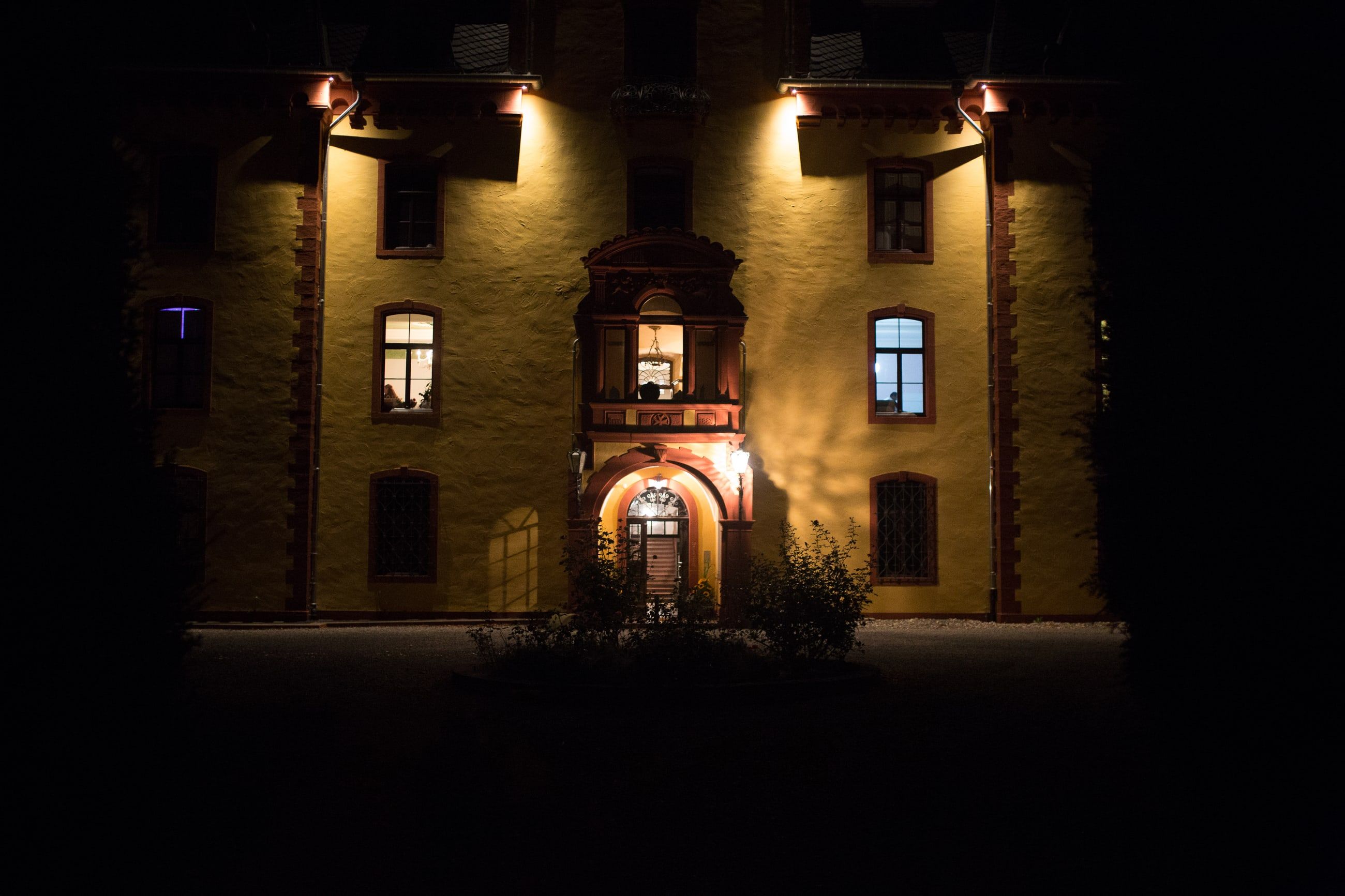 Schloss Wachendorf bei Nacht, die gelbe Fassade mit dem Eingangserker warm angestrahlt vor dunklem Himmel