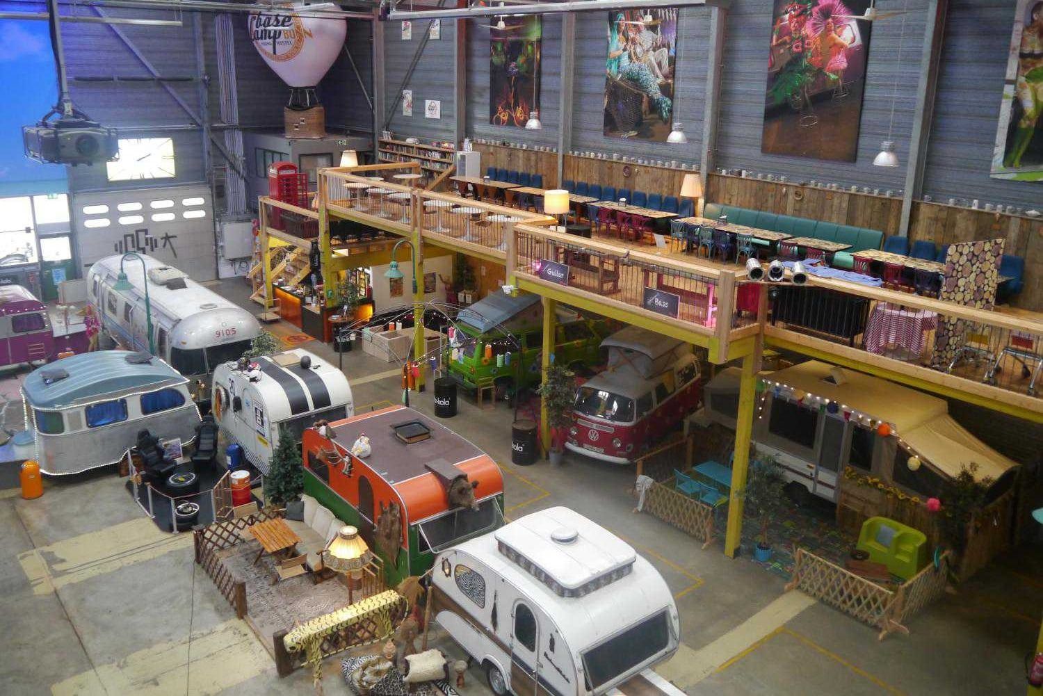 Blick von der Empore über die Halle des BaseCamp mit Wohnwagen, Airstreams, Vorgärten und einem roten Bus