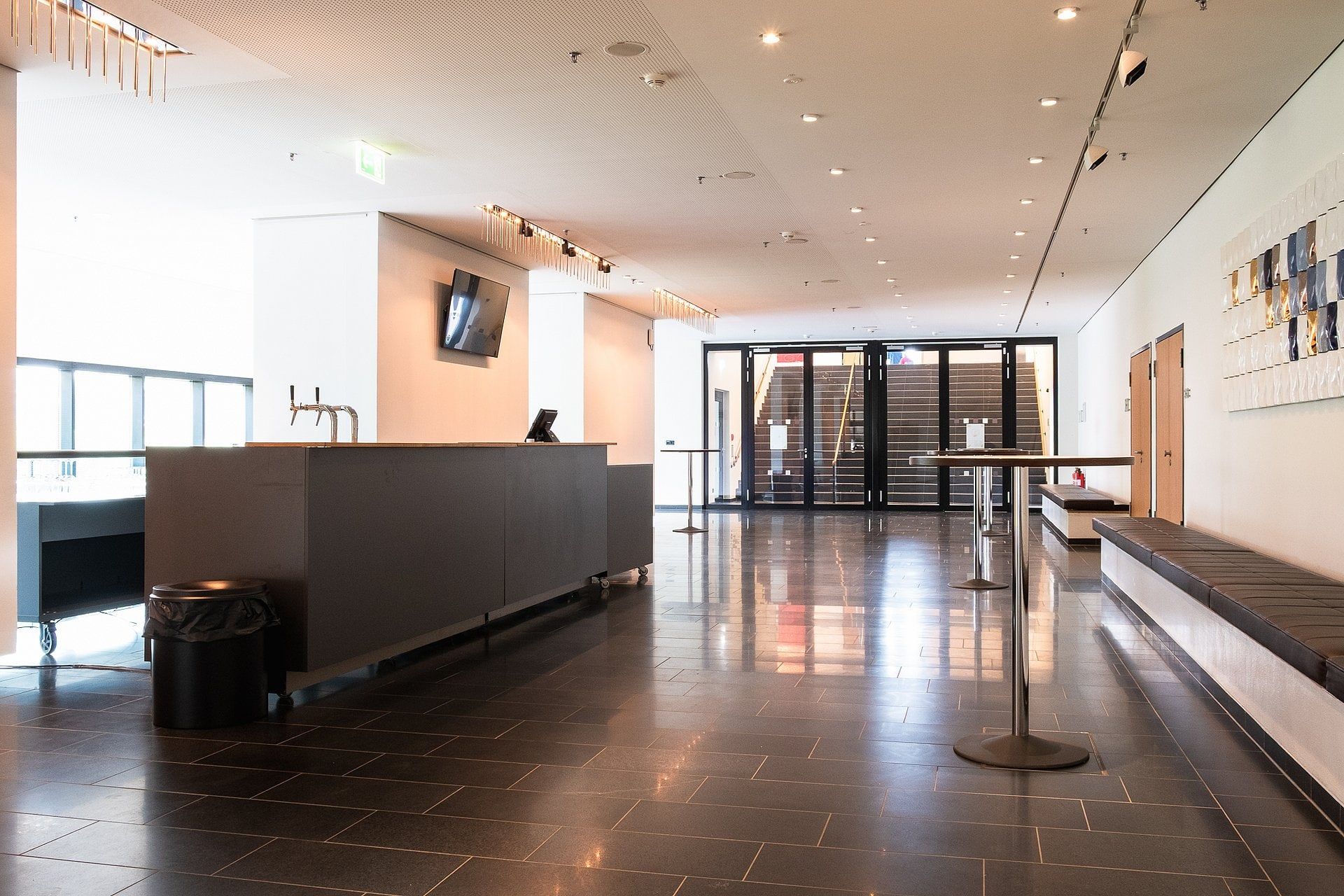 Helles Foyer im Rhein Sieg Forum mit langer dunkler Theke, Steinboden und hohen Fenstern zur Stadt