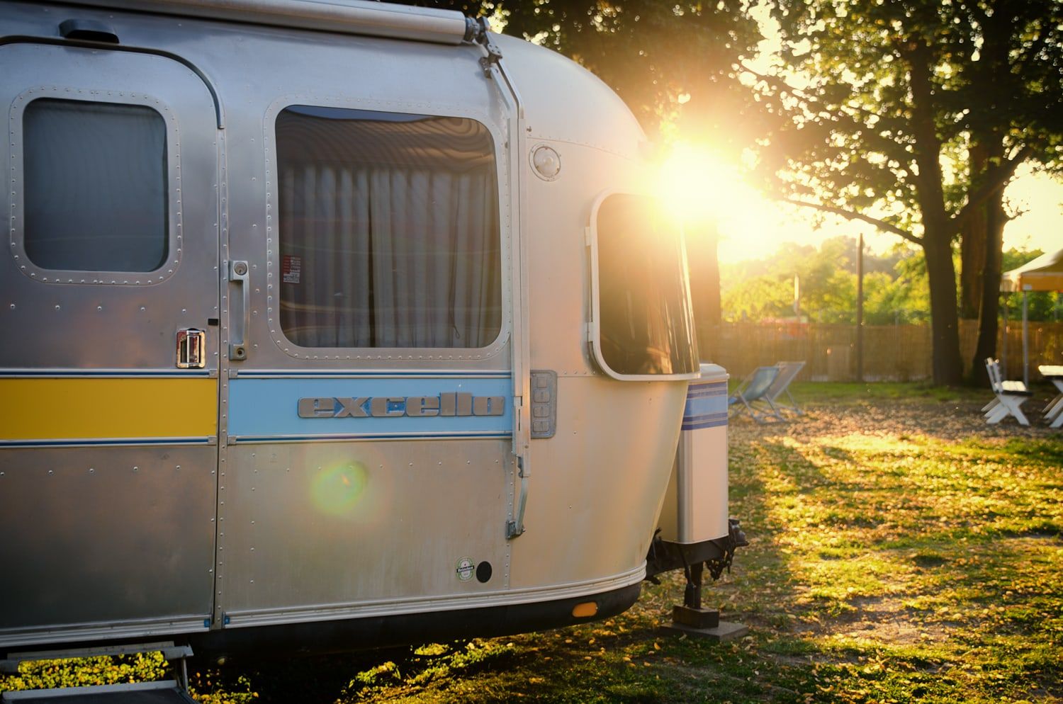 Silberner Airstream-Wohnwagen im Abendlicht unter Bäumen auf dem Außengelände in Bonn
