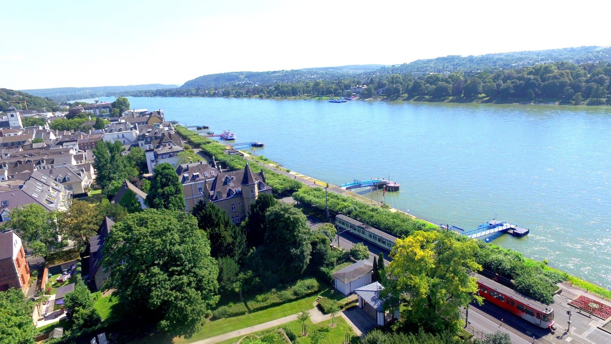 Blick über die Dächer von Königswinter auf die Rheinpromenade und den Rhein mit dem bewaldeten Ufer gegenüber
