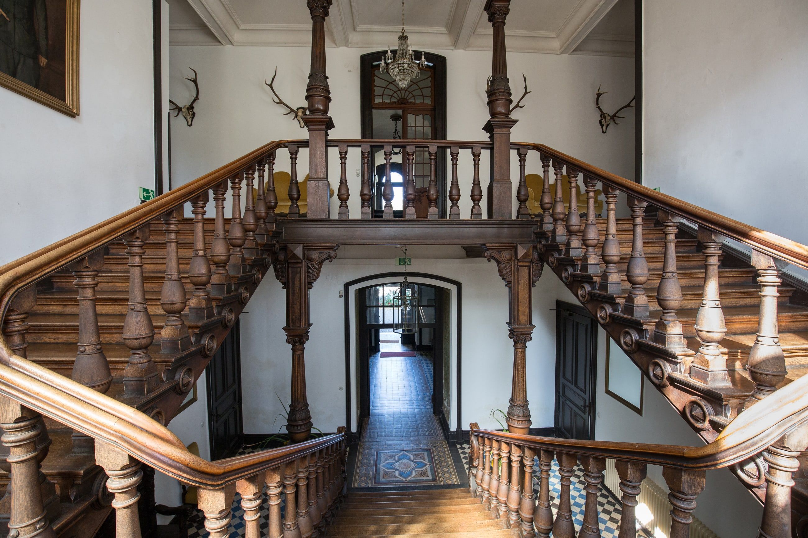 Das Treppenhaus von Schloss Wachendorf mit geschnitzten Holzgeländern und Galerie, symmetrisch von unten gesehen